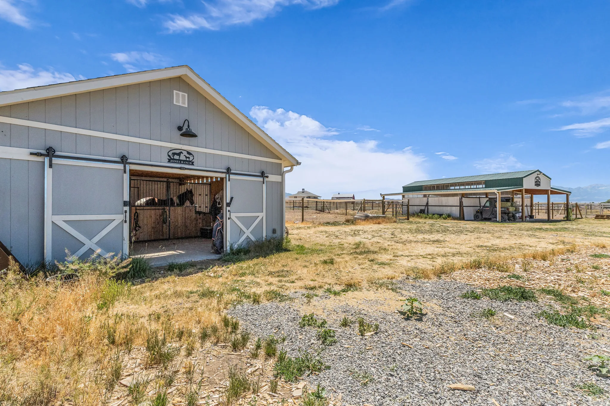 Light gray barn structure featuring a white gable roof and dark trim two stall barn could be used for foaling.