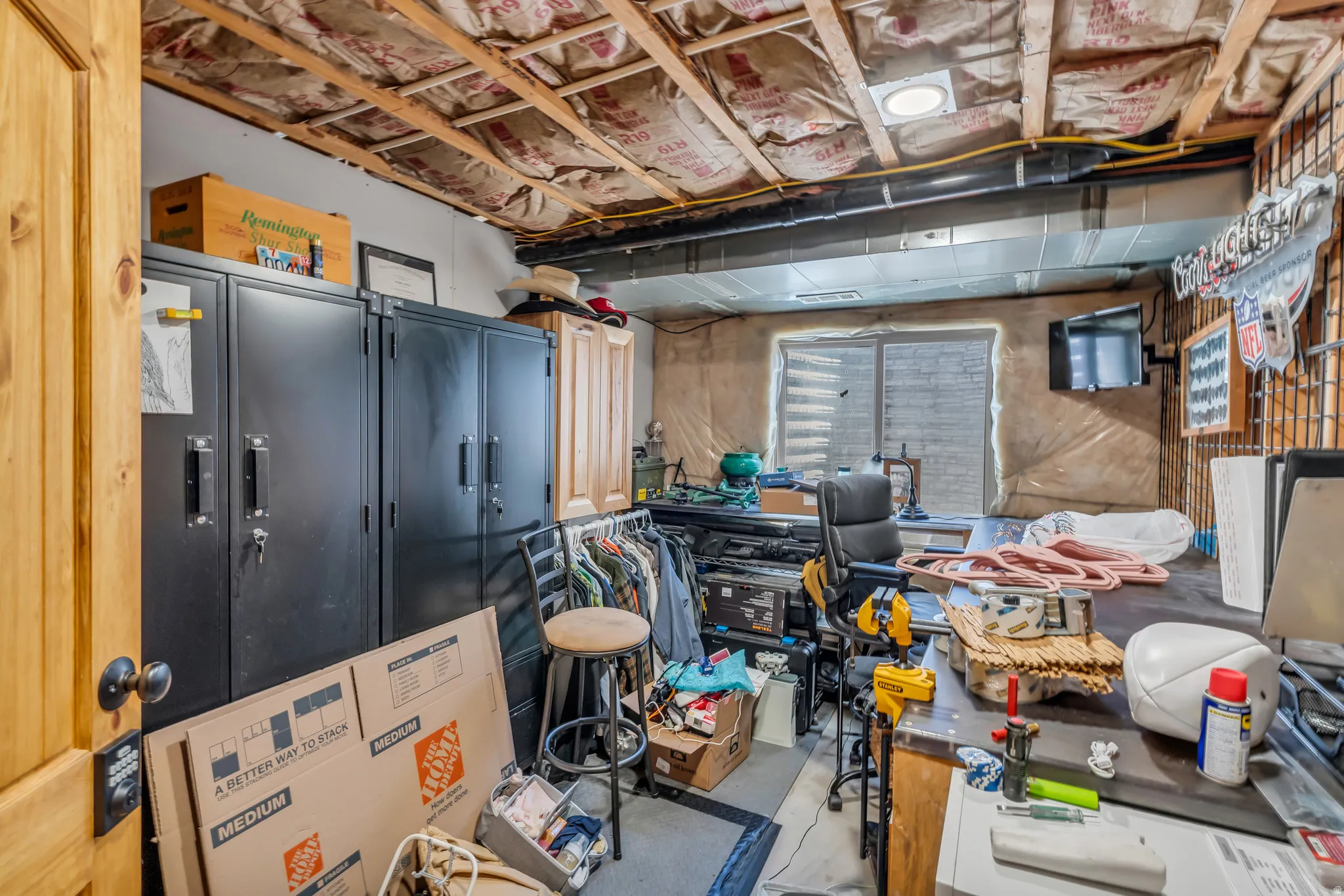 Utility room featuring an exposed joist ceiling with insulation, a window with horizontal blinds, and a wood-finish door