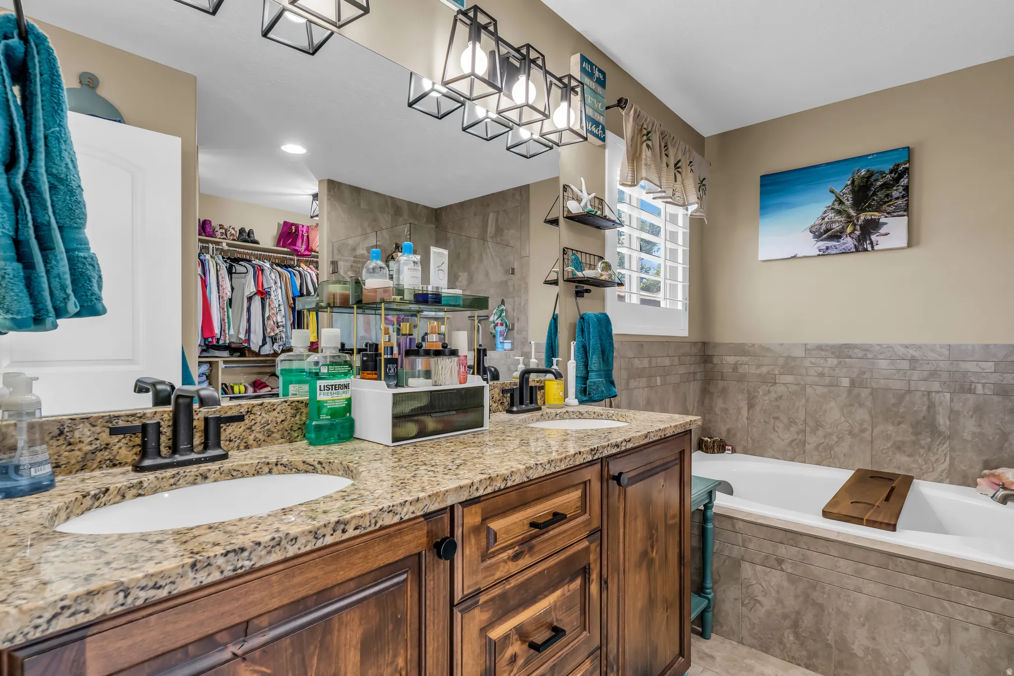 Primary ensuite with dual vanity with granite countertop, dark wood-finish cabinetry, and black hardware