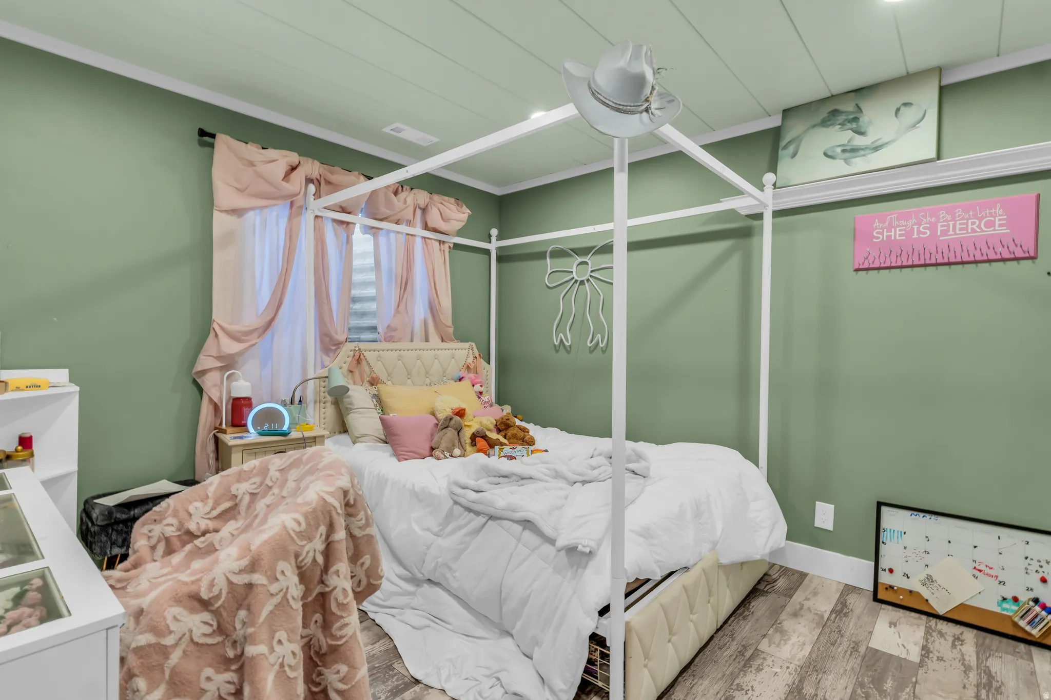 Spacious bedroom featuring light green walls, a paneled ceiling, and wood-finish flooring