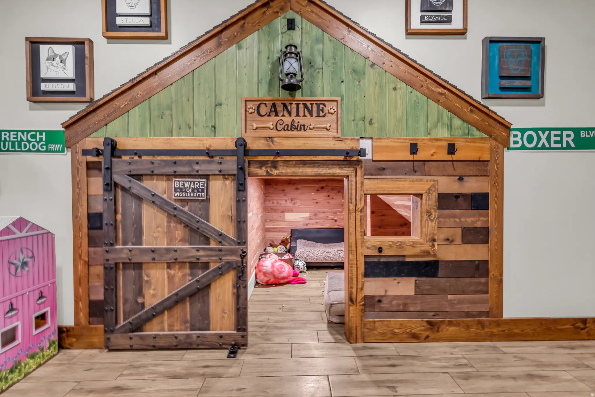 Custom-built pet or play haven featuring a barn-style sliding door, interior window, and wood-finish flooring