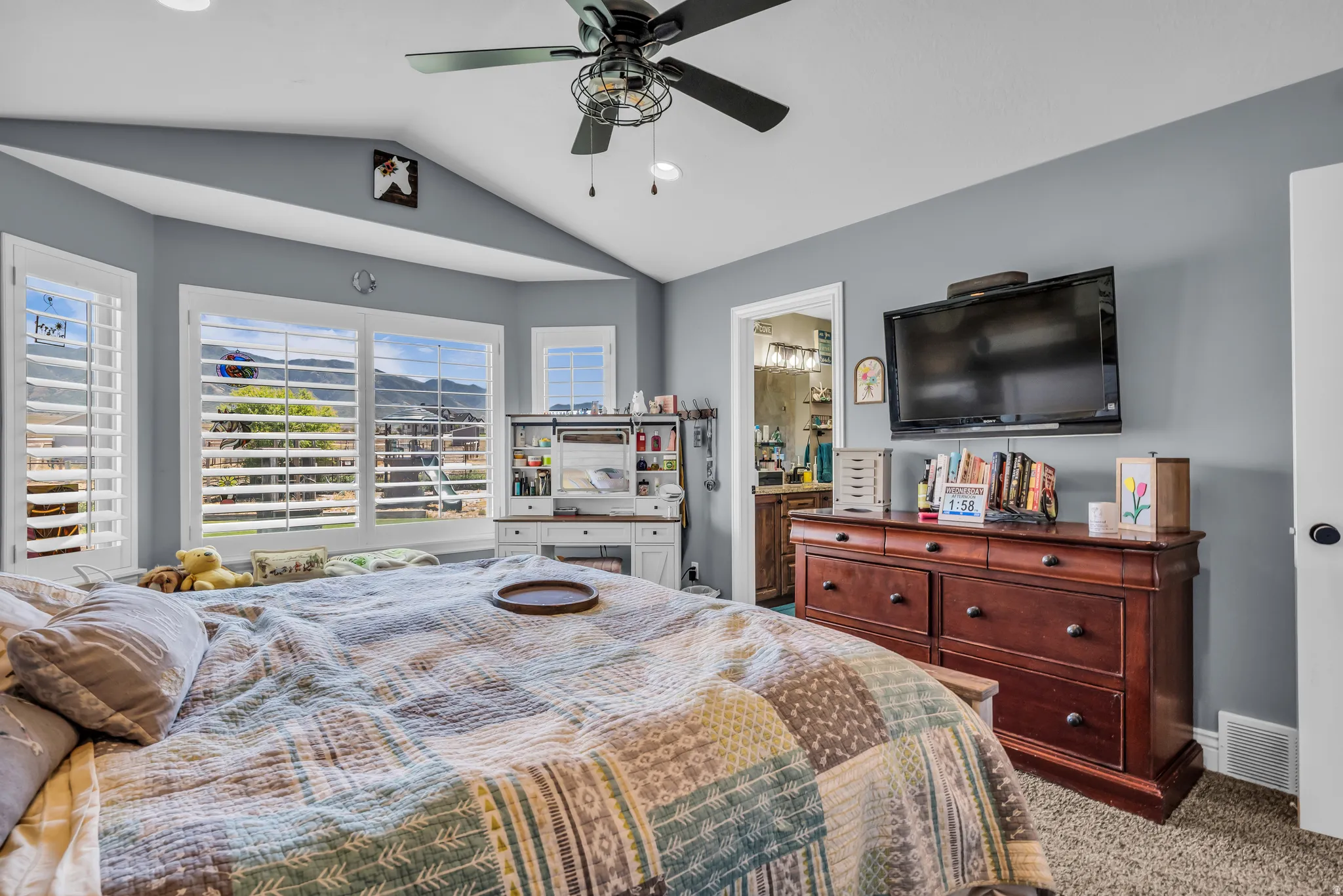 Primary vaulted ceiling room with multiple windows, plantation shutters, and recessed lighting