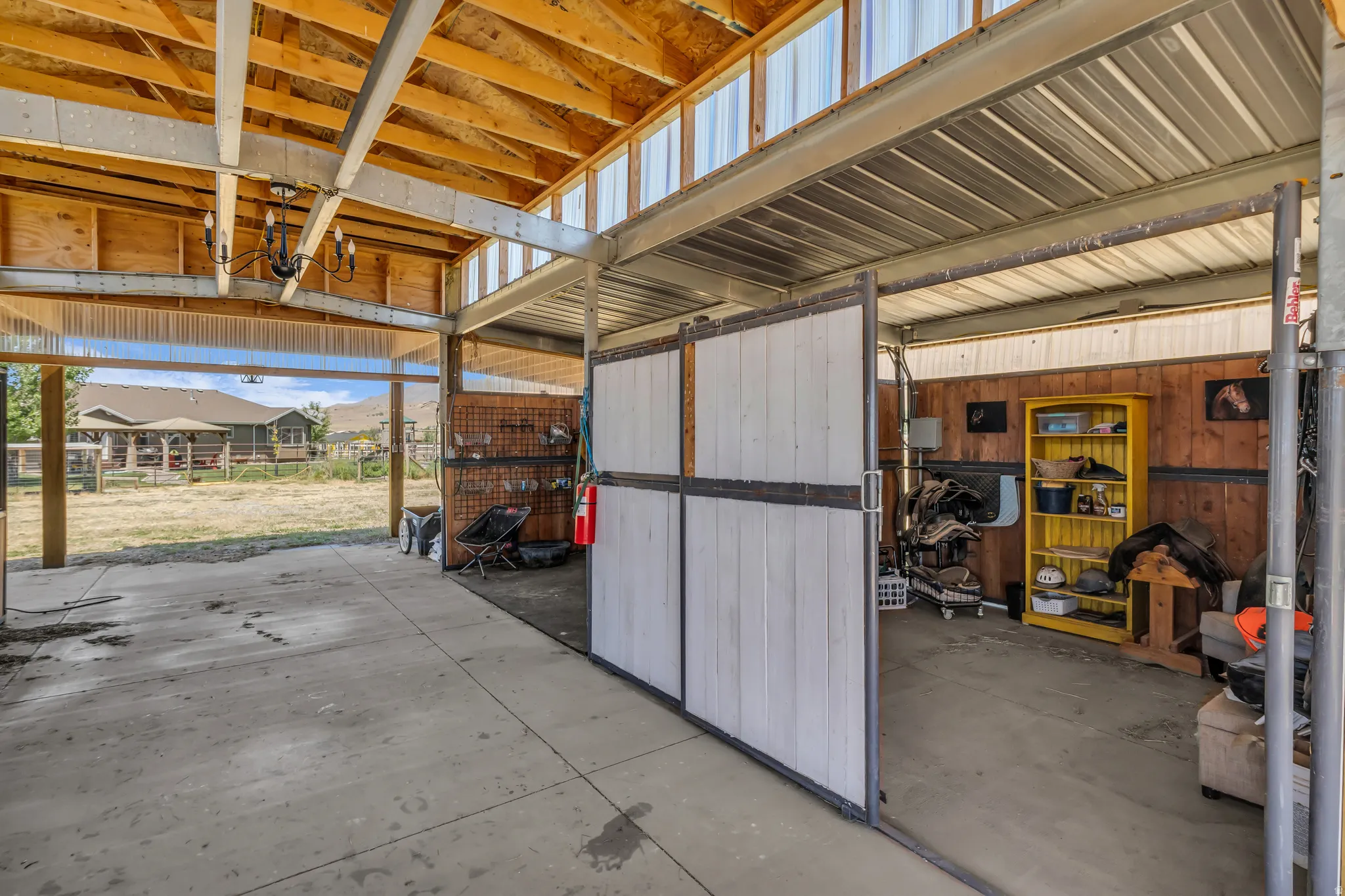 Covered outdoor structure featuring a concrete floor, exposed wood ceiling beams, and a metal roof