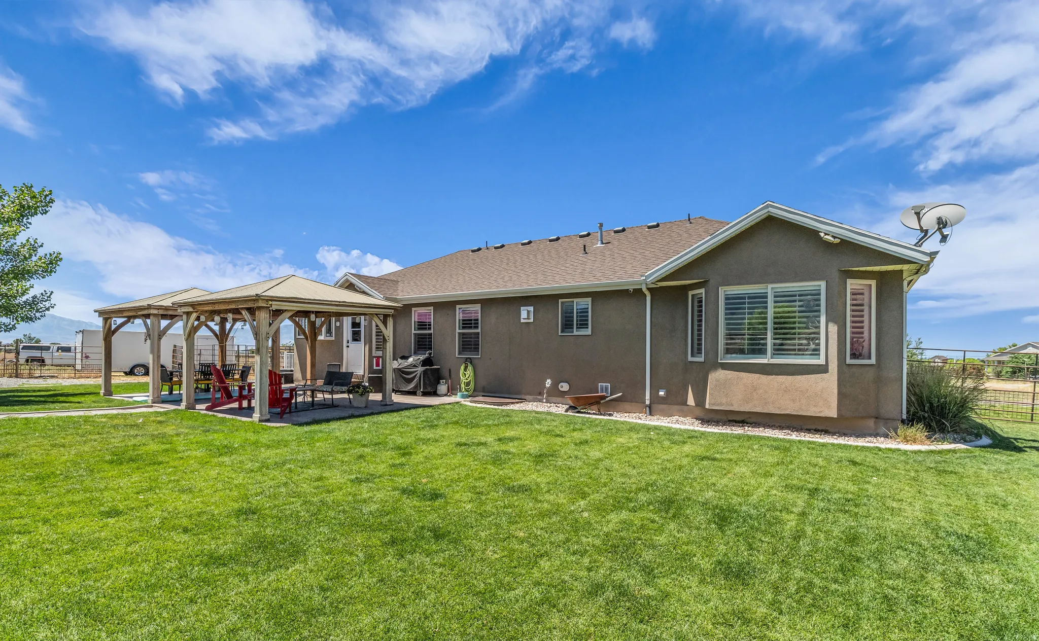 Expansive green lawn with a two-section patio and a wood-frame gazebo