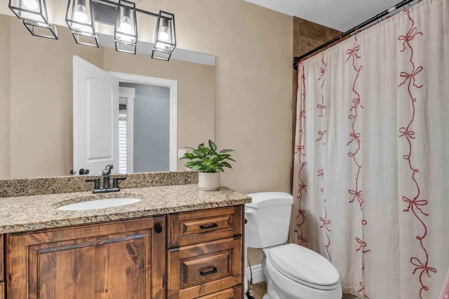 Bathroom vanity featuring a granite countertop with an undermount sink, dark wood cabinetry, and a black faucet