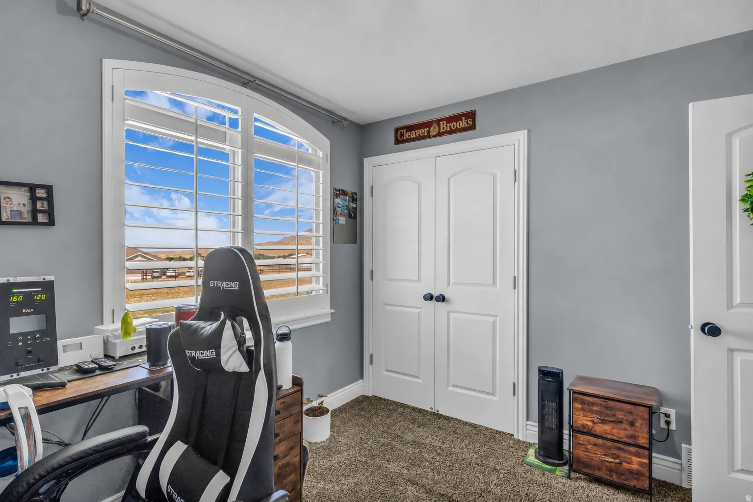 Room featuring an arched window with louvered shutters, light gray walls, and carpet flooring
