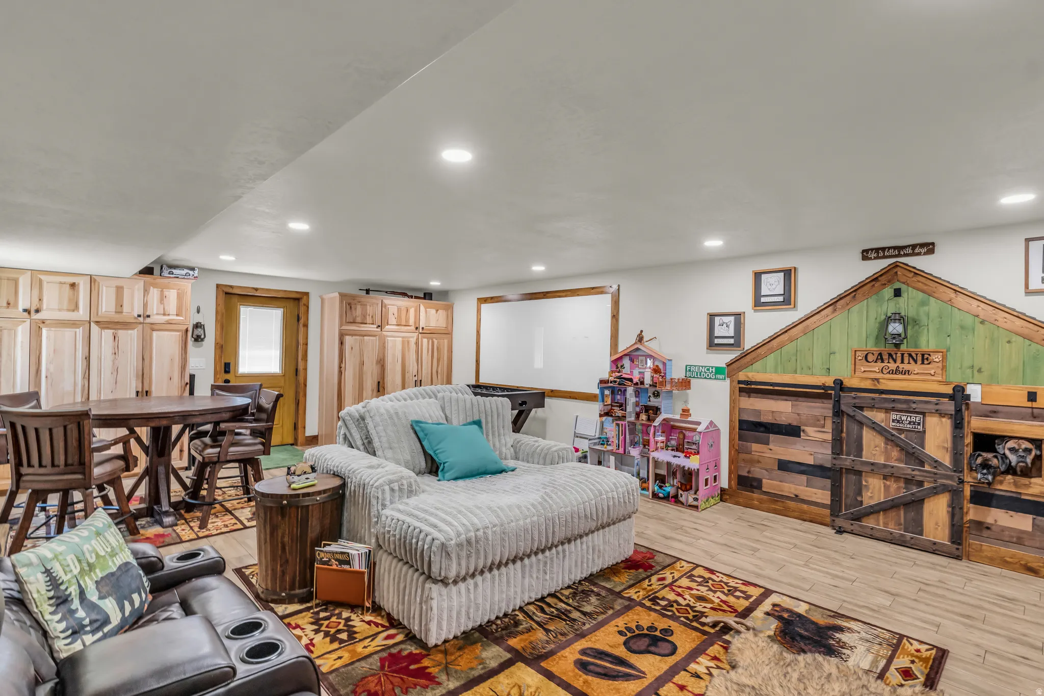 Spacious lower-level area featuring recessed lighting, a wood-finish flooring, and extensive built-in cabinetry with natural wood finishes