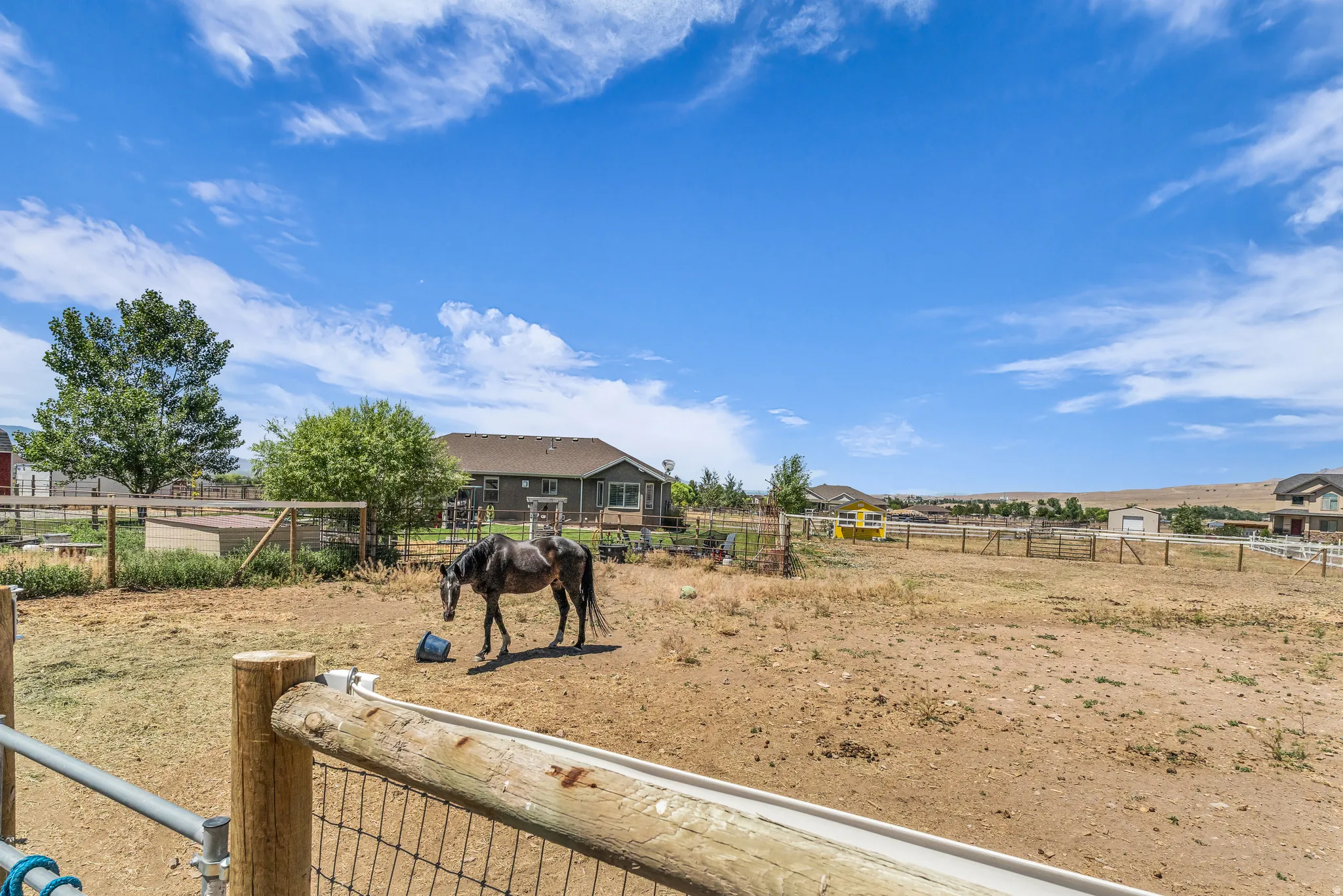 Expansive outdoor area featuring a fenced paddock with a lean-to structure, wood post and wire fencing, and surrounding open terrain