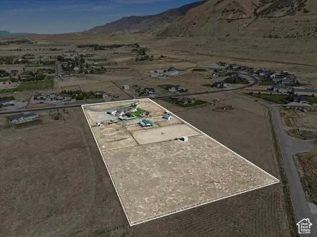 Expansive property outlined by fencing, featuring multiple outbuildings, a circular paddock, and a paved road frontage