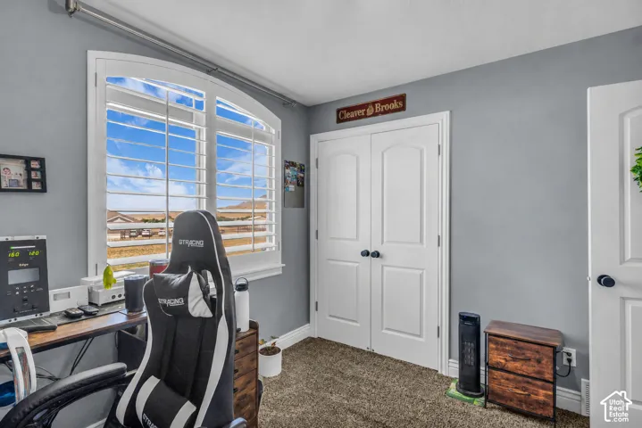 Virtually cleared of items and decor. Bedroom 2 on the main floor. Room featuring an arched window with louvered shutters, light gray walls, and carpet flooring