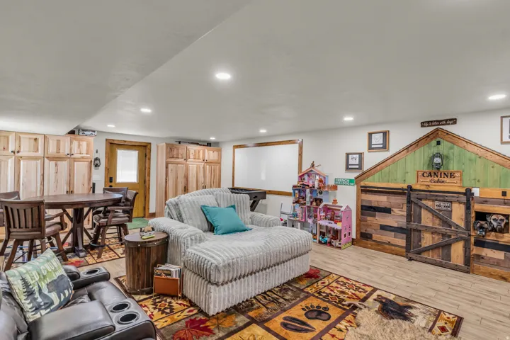 Spacious lower-level area featuring recessed lighting, a wood-finish flooring, under stairs play/dog room and view to the exterior door that leads to the west.