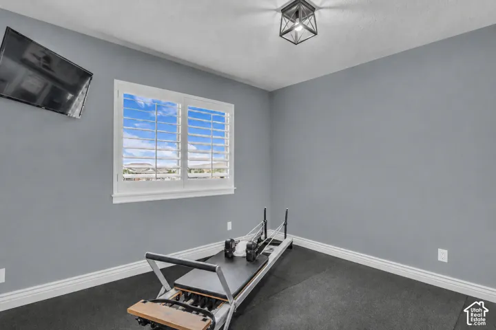 Virtually cleared of items and decor. Bedroom 3. Room featuring a window with white plantation shutters, gray walls, and dark flooring