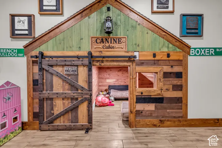 Custom-built pet or play haven featuring a barn-style sliding door, interior window, and wood-finish flooring
