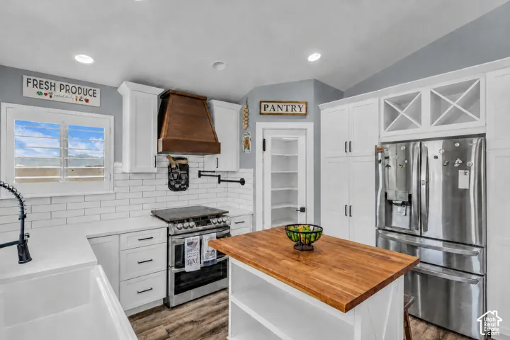 Virtually cleaned and cleared of items and decor. Kitchen featuring white cabinetry, wood-finish flooring, and subway tile backsplash, 2 kitchen islands and walk-in pantry
