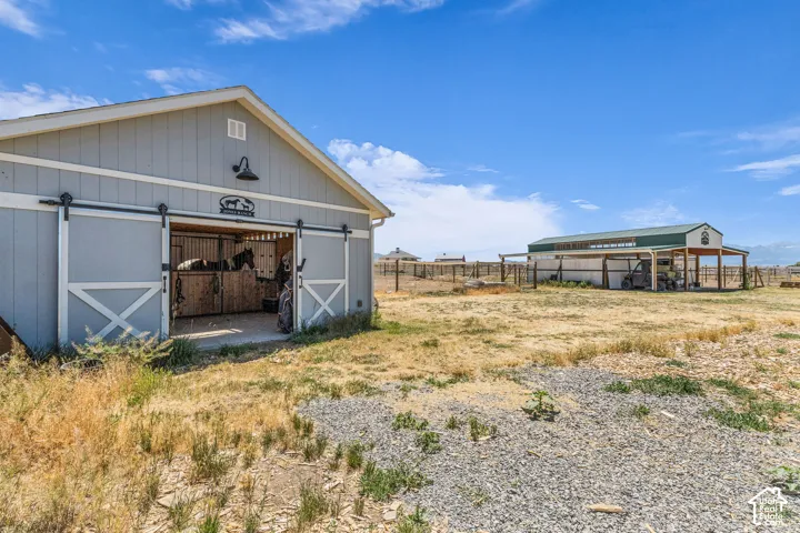 Light gray barn structure featuring a white gable roof and dark trim two stall barn could be used for foaling.