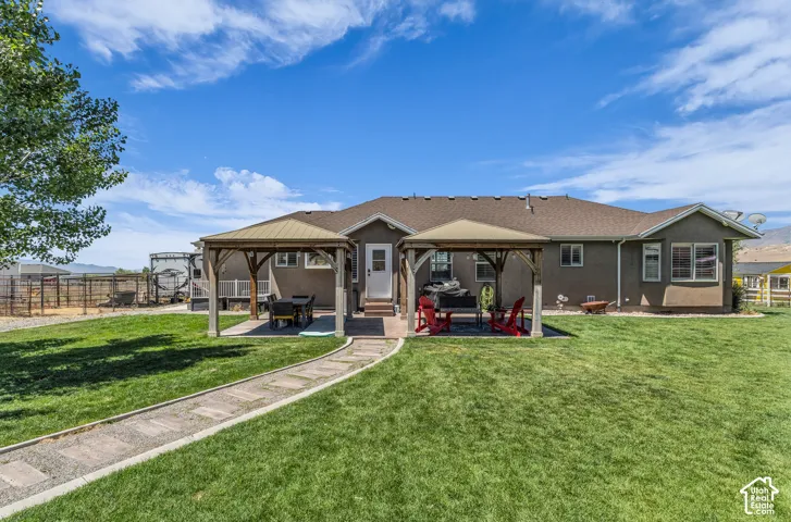 Spacious rear yard with a stone paver pathway, two permanent gazebos, and an expansive lawn area