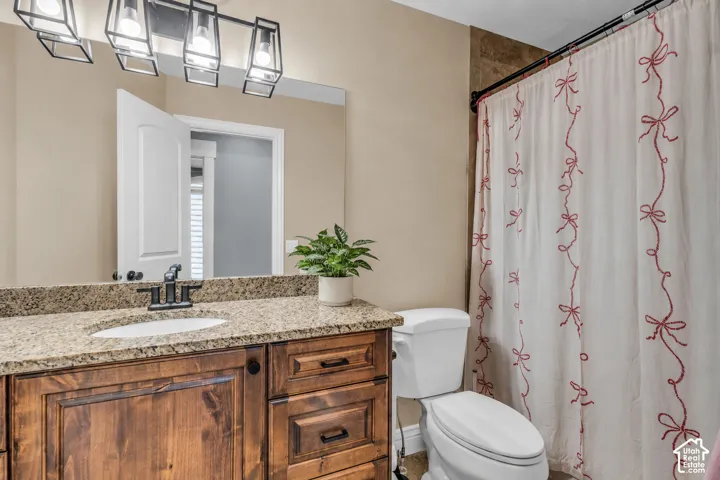 Virtually cleared of items and decor. Bathroom vanity featuring a granite countertop with an undermount sink, dark wood cabinetry, and a black faucet
