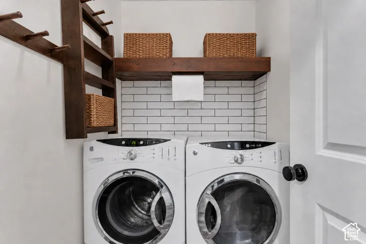 Virtually cleared of items and decor. Dedicated laundry area featuring a white subway tile backsplash, a dark wood-finish floating shelf, and a dark wood-finish wall-mounted organizer