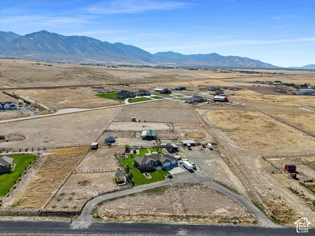 Expansive property featuring a residence with an attached garage, landscaped grounds with green lawn, and surrounding open fields