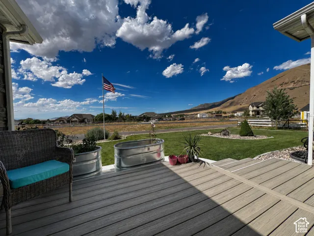 Spacious outdoor deck featuring composite decking, a manicured lawn area, and mountain scenery
