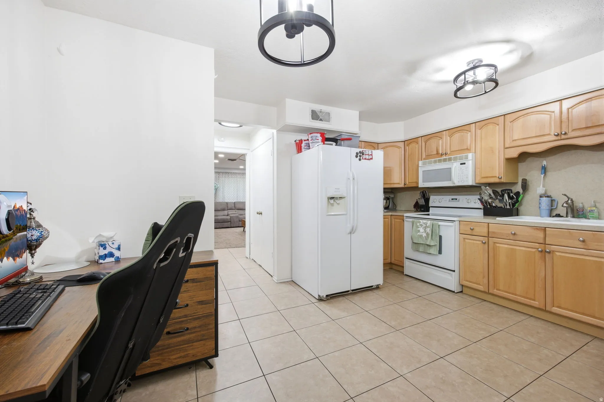 Kitchen featuring light wood cabinetry, white appliances, and a double-basin sink