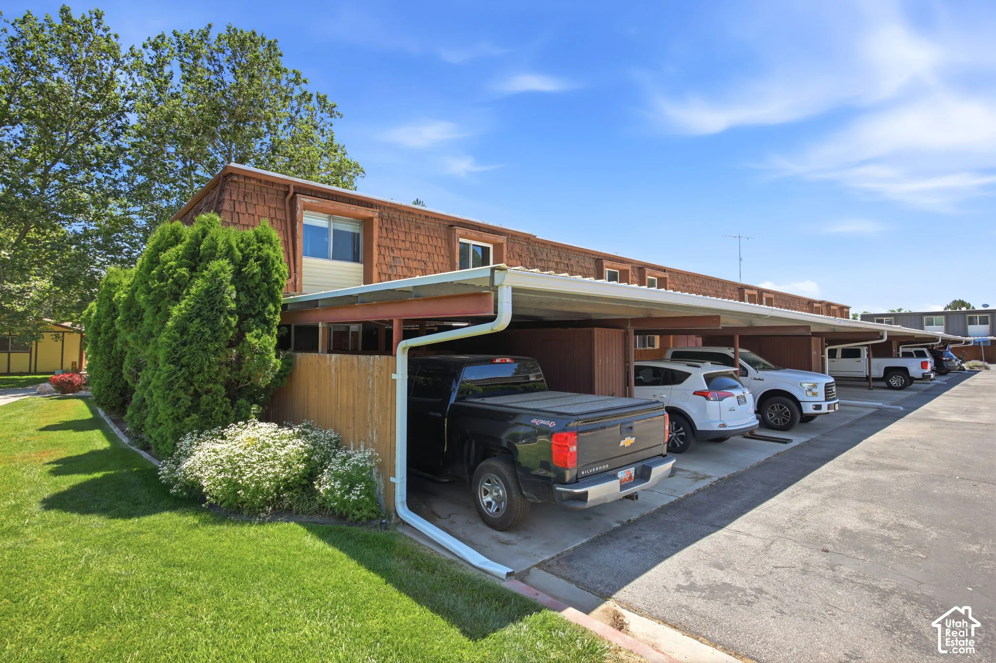 Exterior featuring wood shake siding, neutral vinyl siding accents, and a continuous covered parking structure