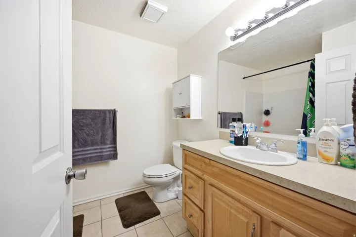 Bathroom featuring a light wood-finish vanity with an integrated sink, a large wall-mounted mirror, and tile flooring