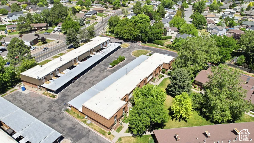 Multi-building property featuring brick exterior construction, ample surface parking, covered parking structures, and mature landscaping