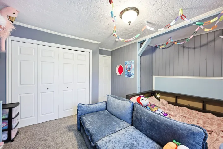 Textured ceiling with a surface-mounted light fixture, carpeted flooring, and white bi-fold closet doors