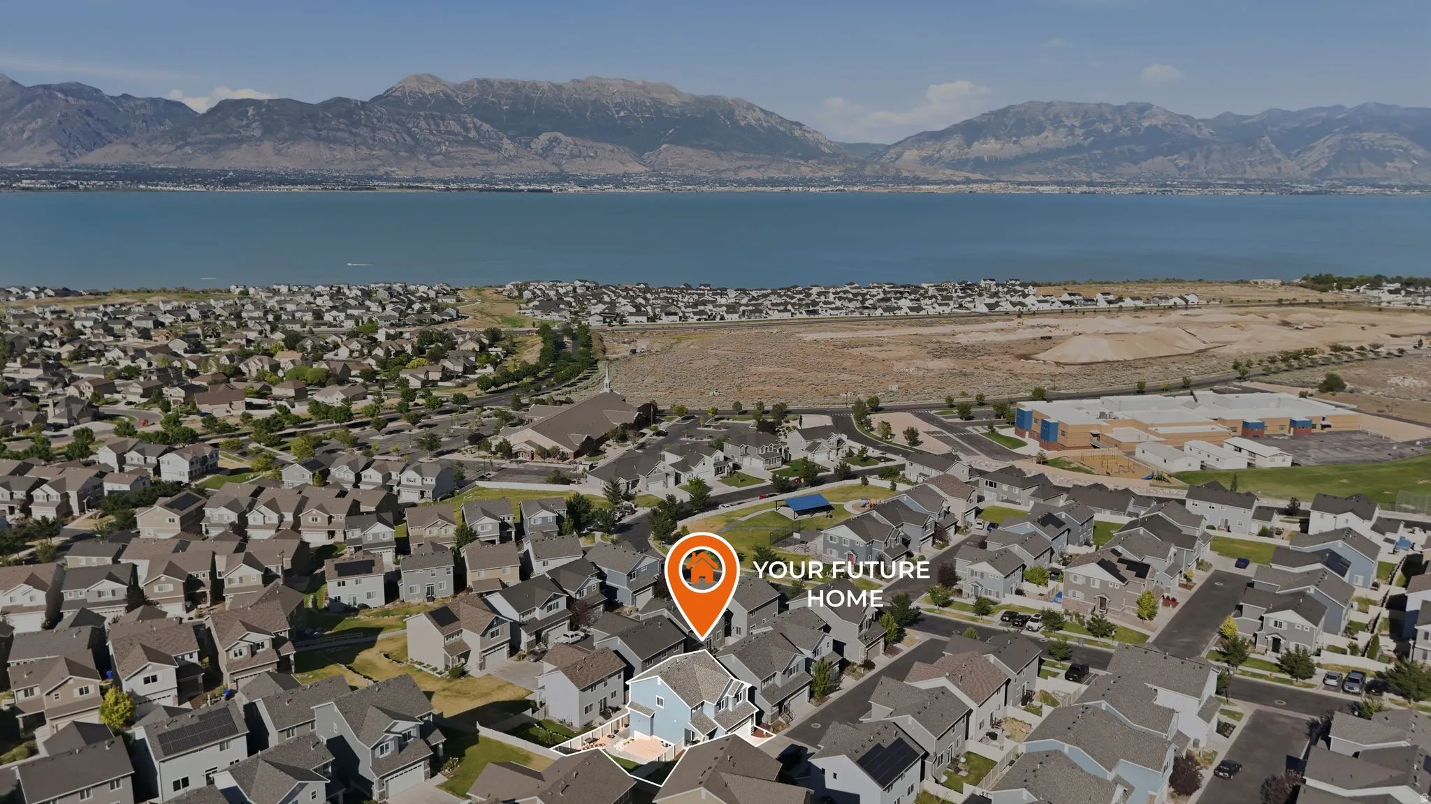 Aerial perspective showcasing a residential community with a large body of water and mountains in the background