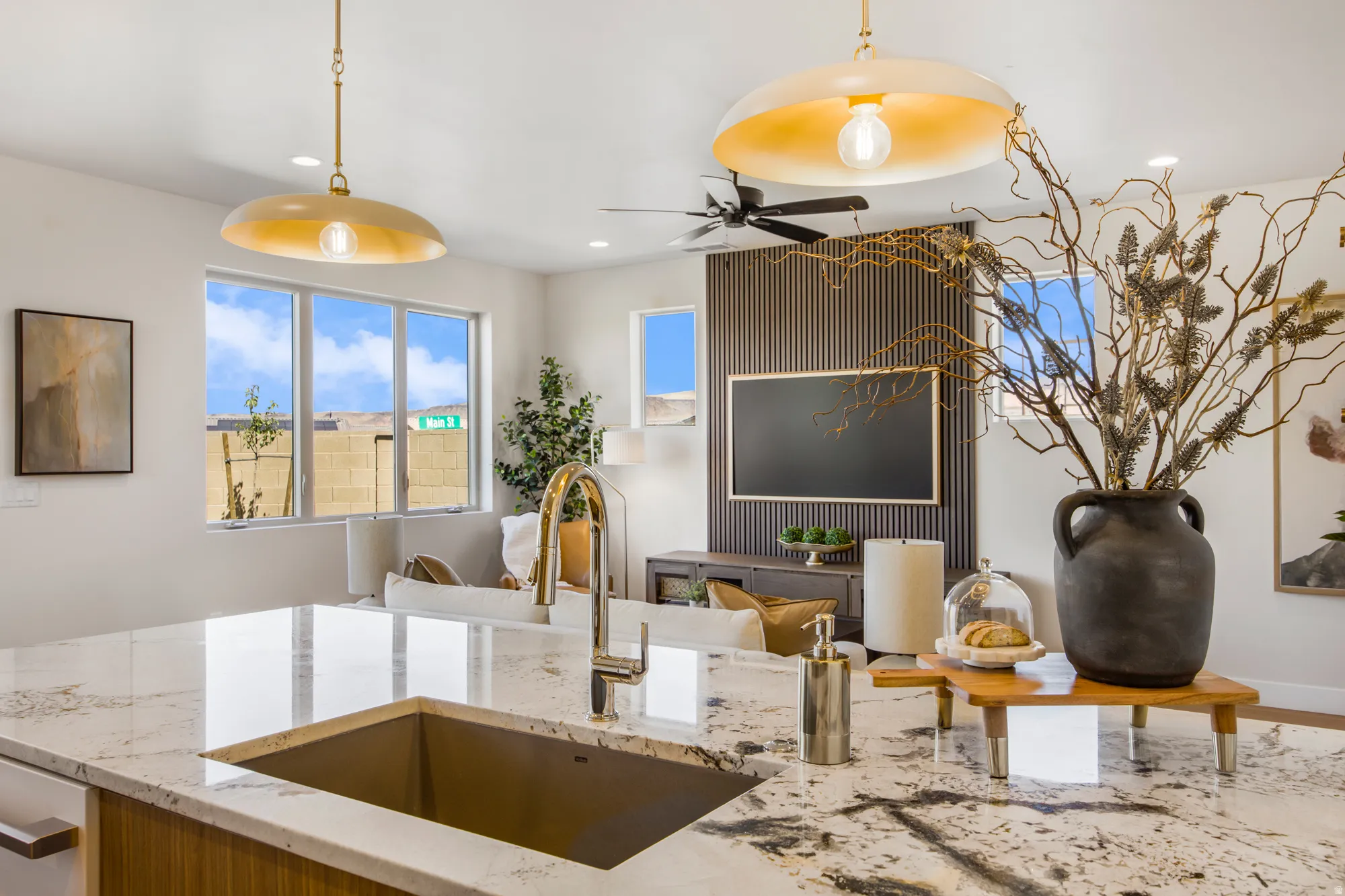 Kitchen island featuring a gold-toned sink, polished gold-toned faucet, and a stone countertop