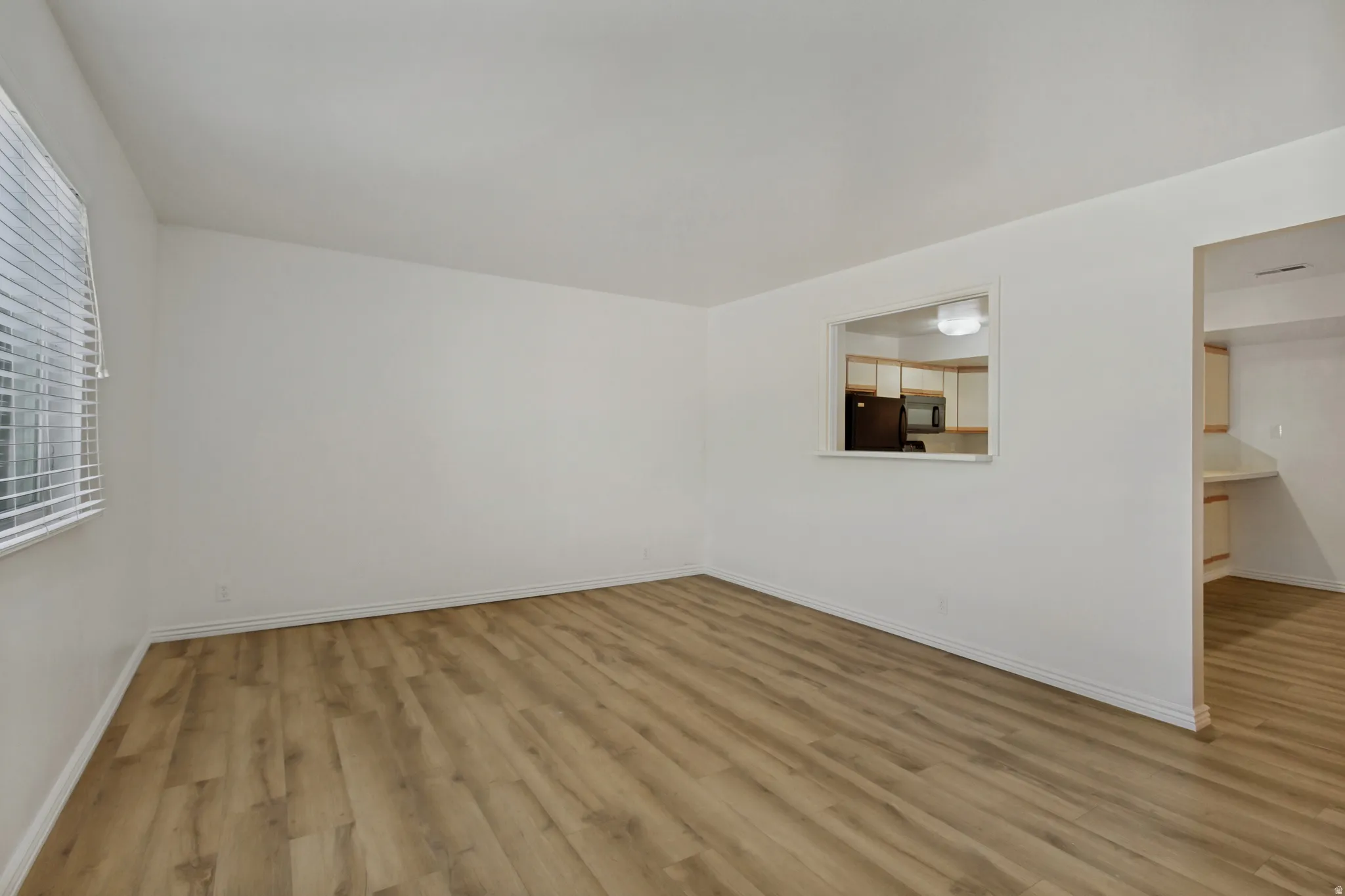 Spacious room with wood-finish flooring and white walls