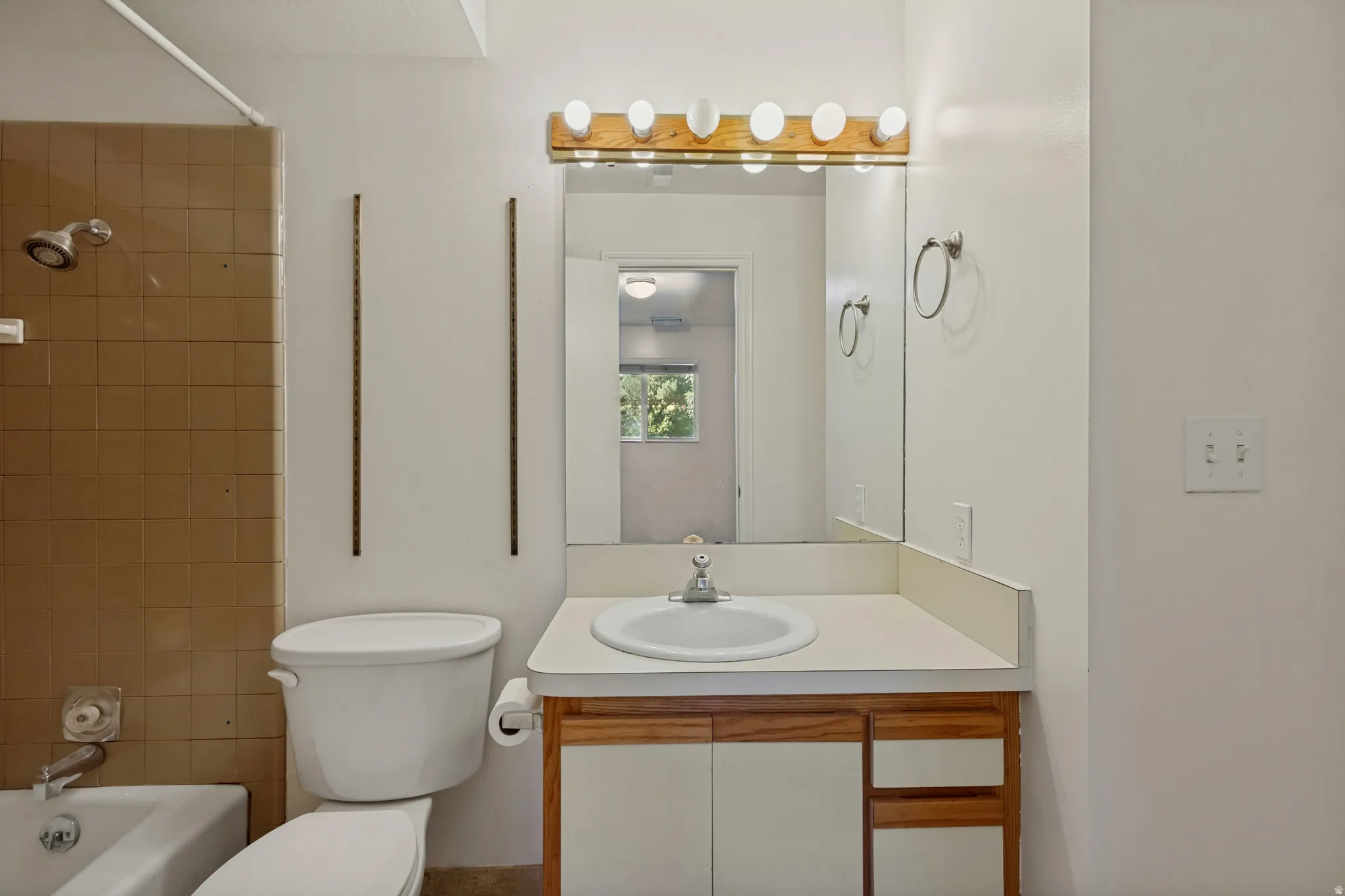 Bathroom featuring a single vanity with wood-finish cabinetry, white countertop, and an integrated sink