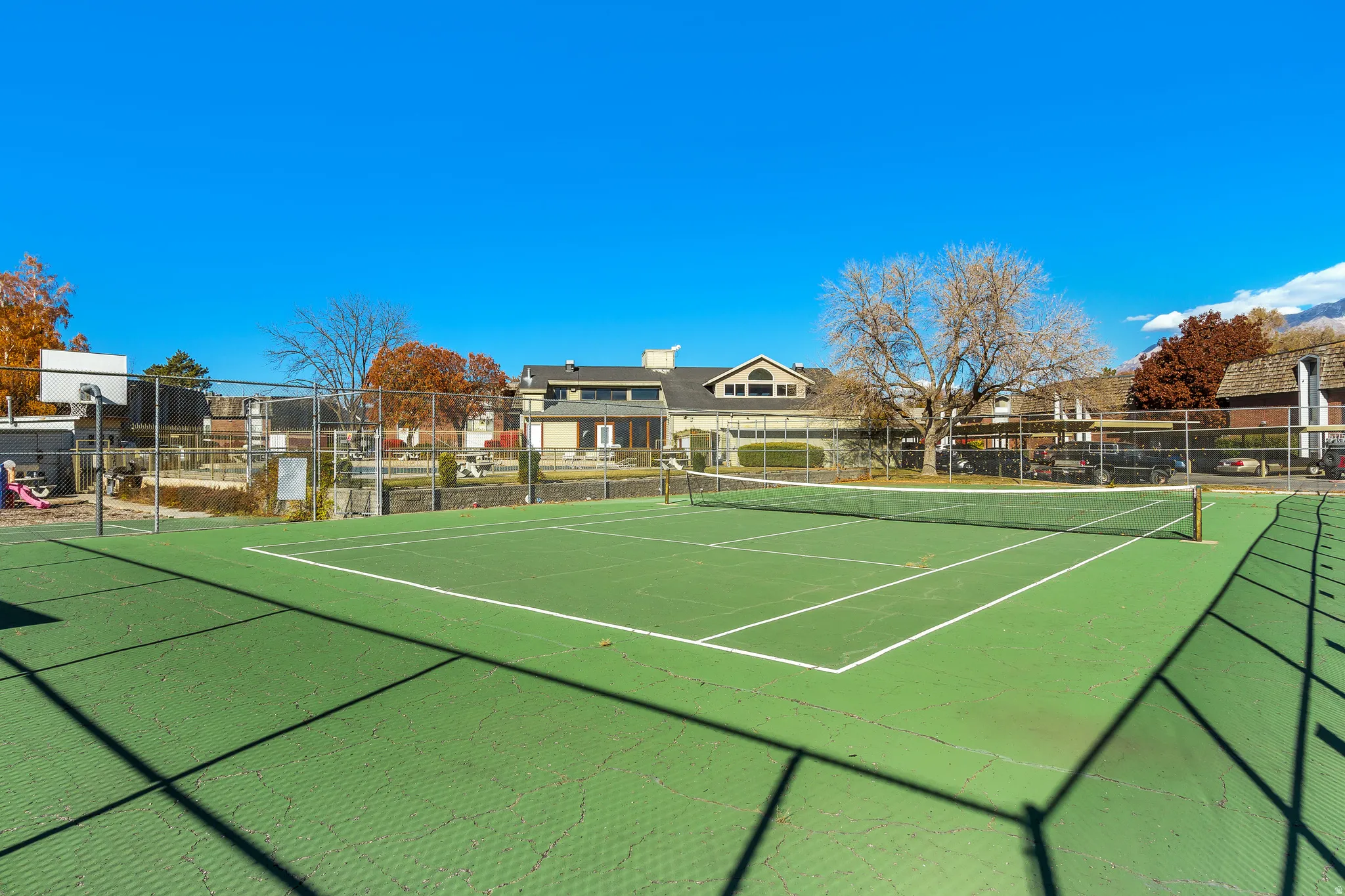 Outdoor tennis court featuring green surfacing and white court lines