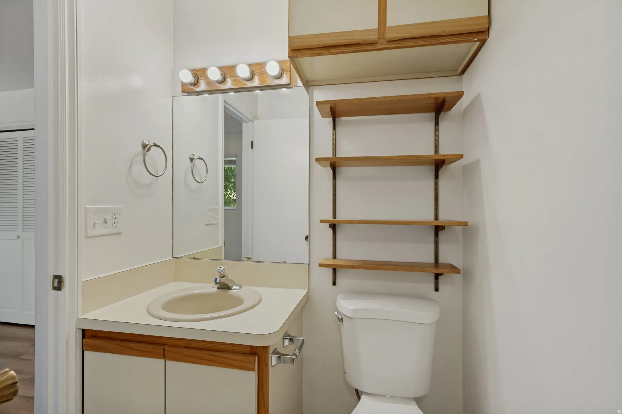 Vanity with integrated sink, wood-finish cabinetry, wall-mounted mirror, and overhead lighting fixture