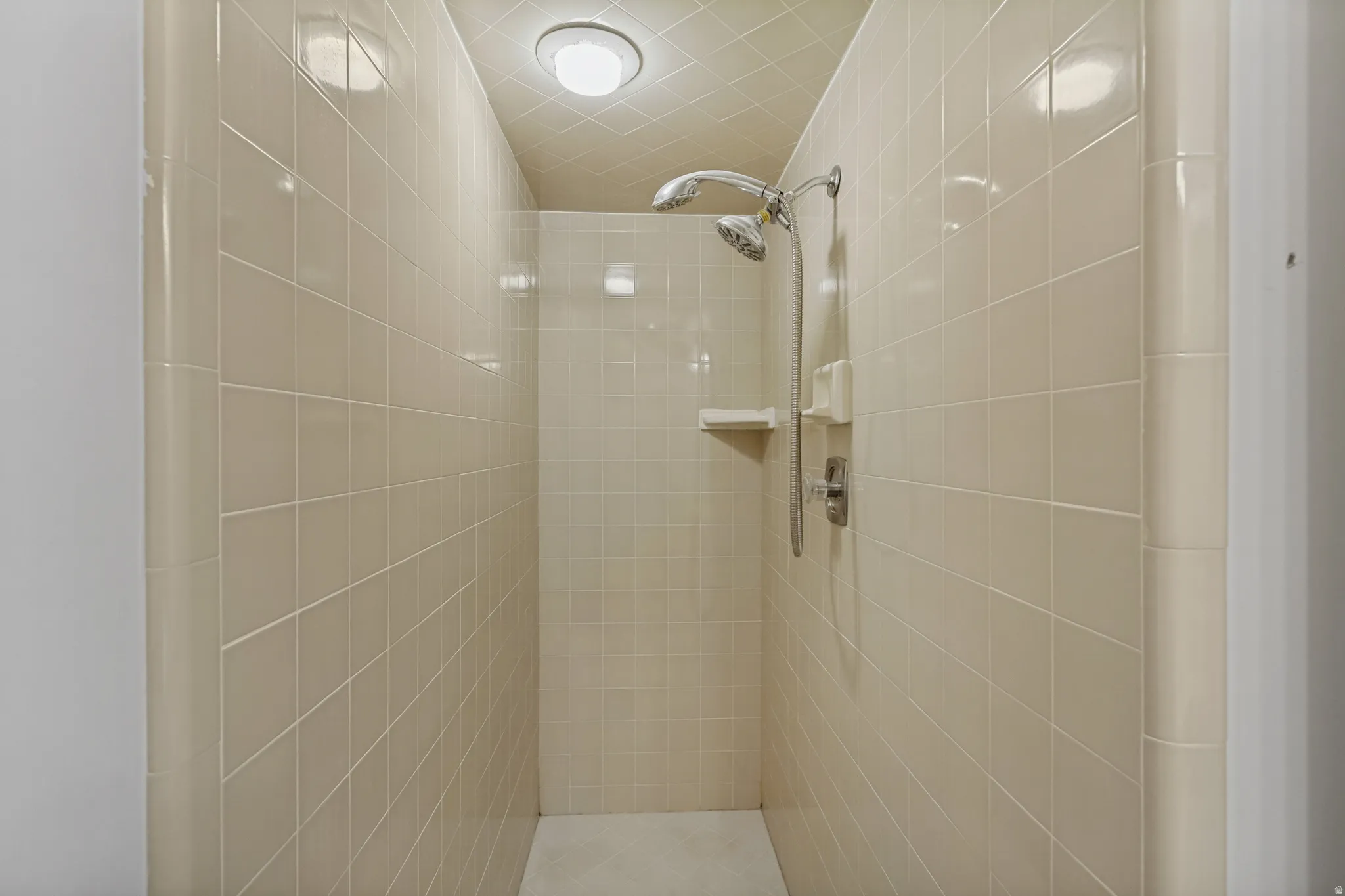 Tiled shower enclosure with a dual shower head system and built-in shelving