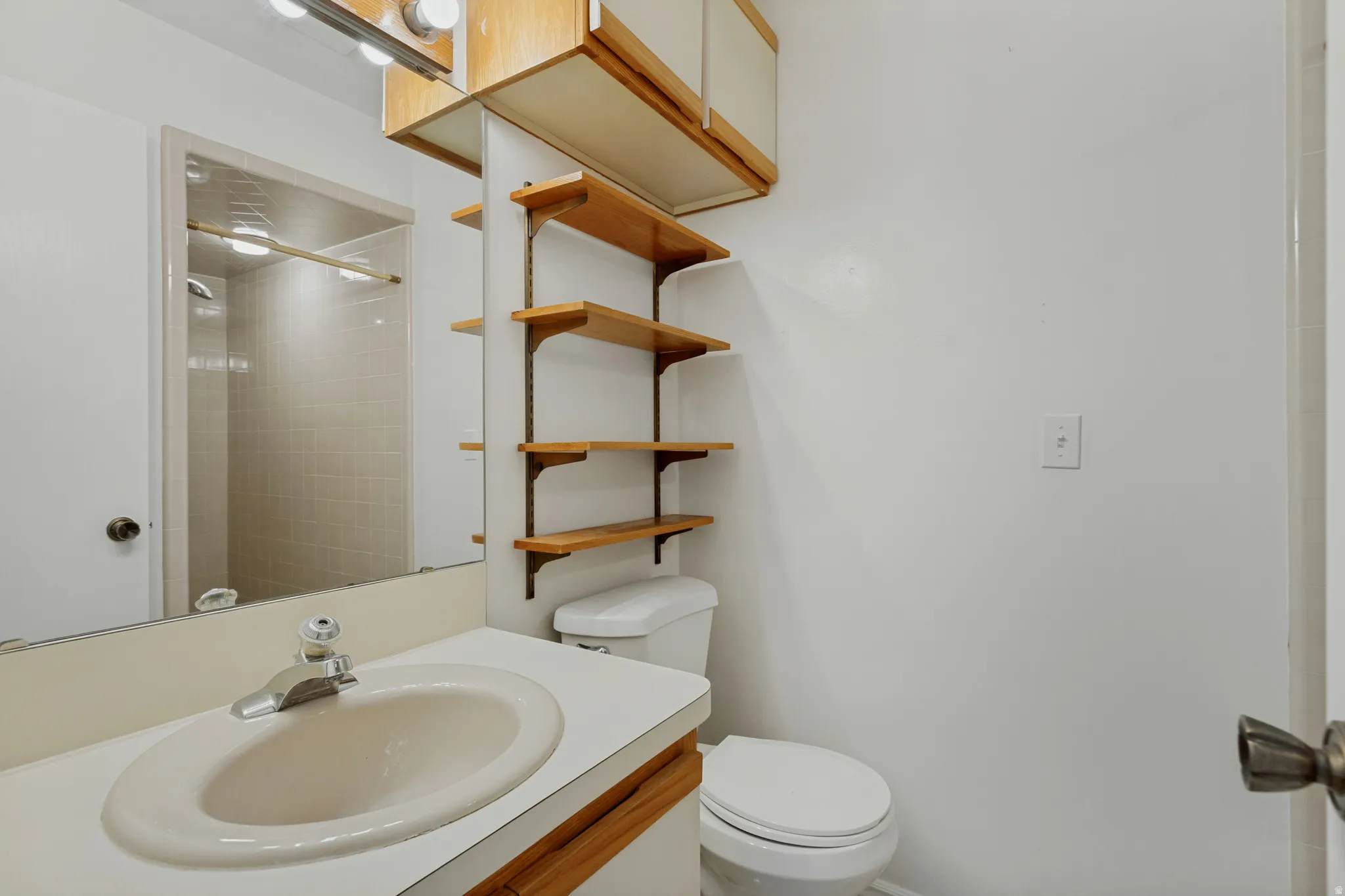 Vanity with integrated sink, overhead lighting, wood-finish cabinetry, and open shelving