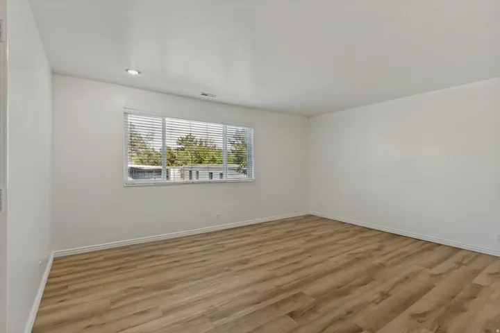 Recessed ceiling lighting, wood-finish flooring, and a large window with blinds
