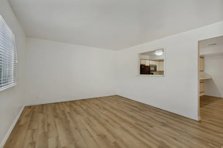 Spacious room with wood-finish flooring and white walls