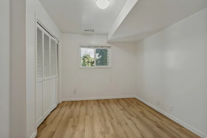 Wood-finish flooring, white walls, and a window for natural illumination