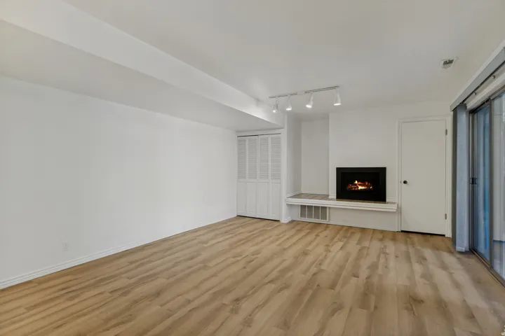 Wood-finish flooring, built-in fireplace with hearth, track lighting, sliding glass door, and bi-fold closet doors
