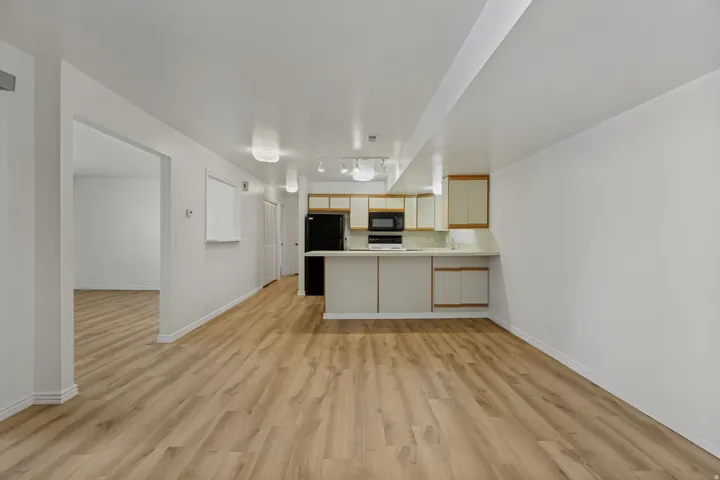 Open-concept living area with wood-finish flooring, white walls, and track lighting
