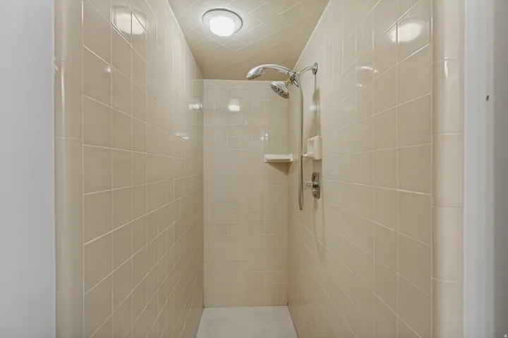 Tiled shower enclosure with a dual shower head system and built-in shelving