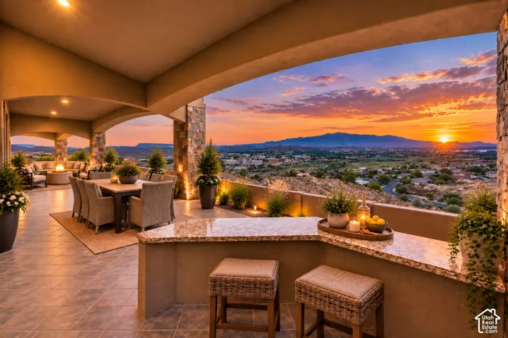 Expansive covered patio featuring a tiled floor, stone columns, built-in counter bar with a polished countertop, and recessed lighting