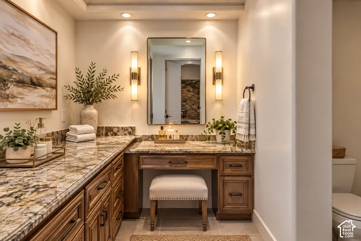 Expansive vanity featuring a stone countertop, wood cabinetry, recessed lighting, and wall sconces flanking a mirror