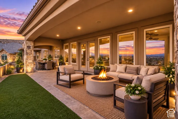 Expansive covered patio with stone flooring, recessed lighting, a built-in fire pit, and full-height windows