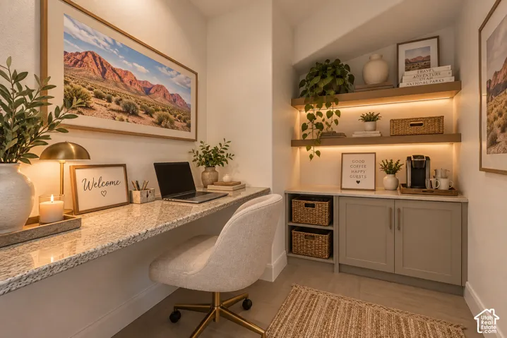 Built-in desk with a stone-finish countertop, custom cabinetry, and integrated shelving with under-shelf lighting