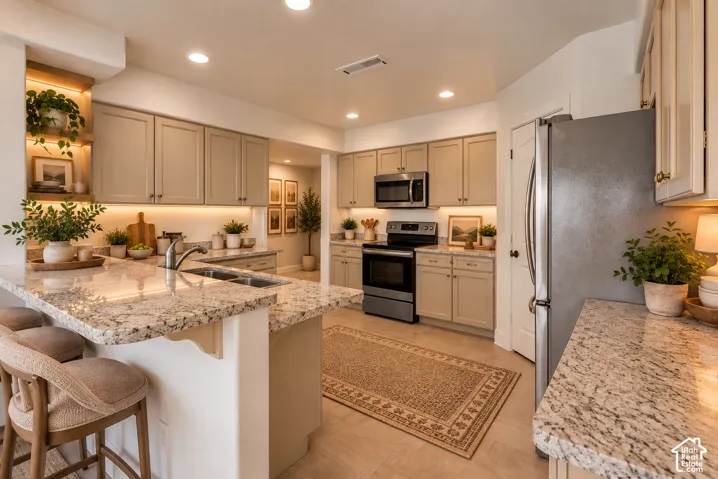 Kitchen featuring light-toned cabinetry, stainless steel appliances, granite countertops, and recessed lighting