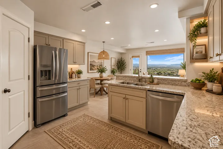 Open-concept kitchen with light-toned cabinetry, stainless steel appliances, recessed lighting, and granite countertops