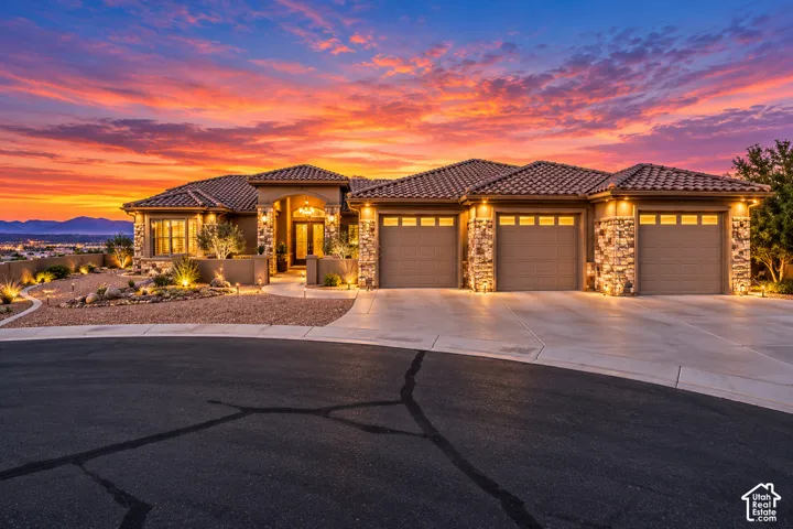 Stone facade with a tile roof, three-car garage, and desert-style landscaping
